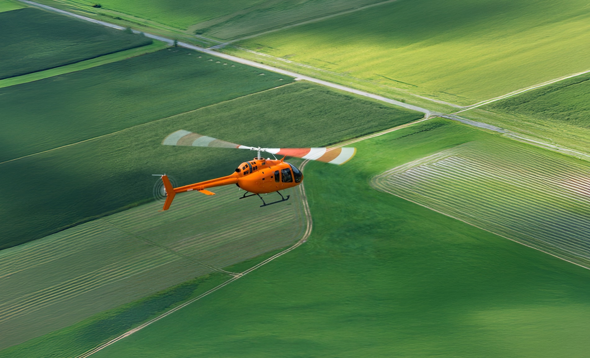 Flight School Next Bell 505 survolant un terrain vert